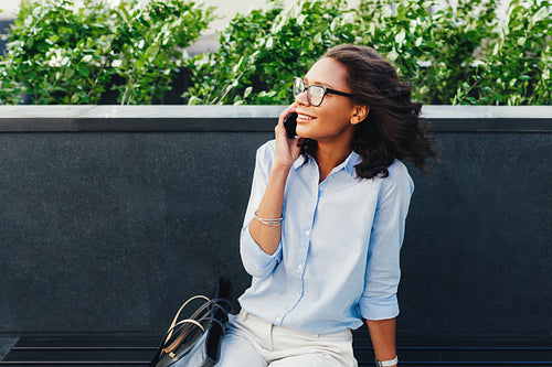 Female entrepreneur sitting outdoors using mobile phone