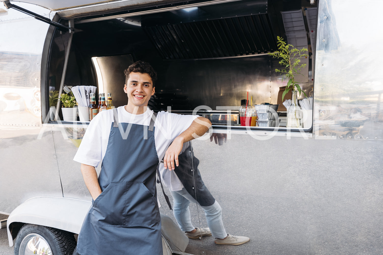 Portrait of a confident salesman leaning on a food truck looking at camera