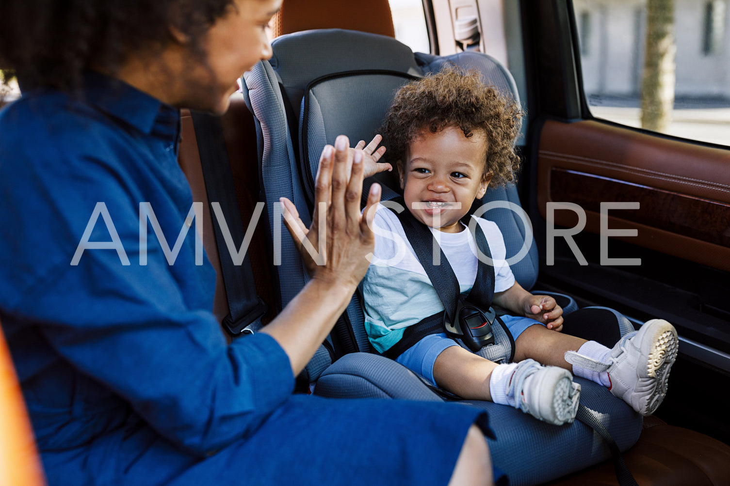 Young mother playing with her son in the car. Two people sitting on a backseat.