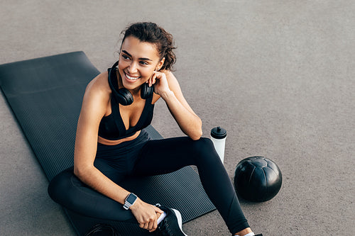 Healthy fit woman in sportswear resting on a mat after exercising at evening