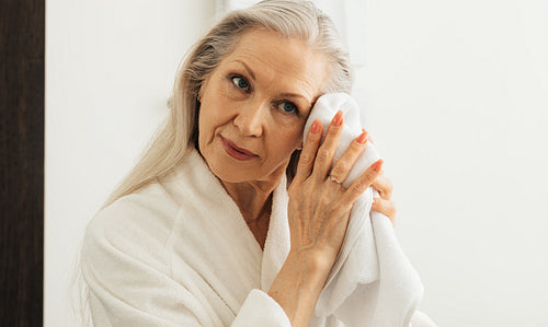 Woman with grey hair wiping her face