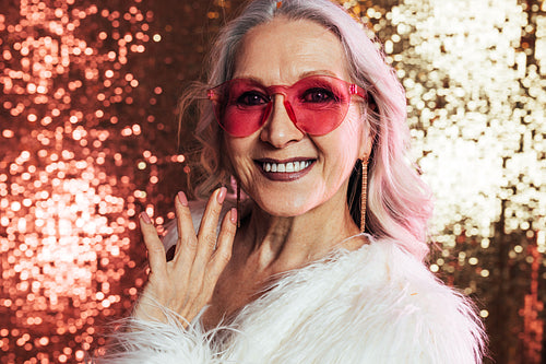 Close up of a smiling senior woman with grey hair wearing pink e