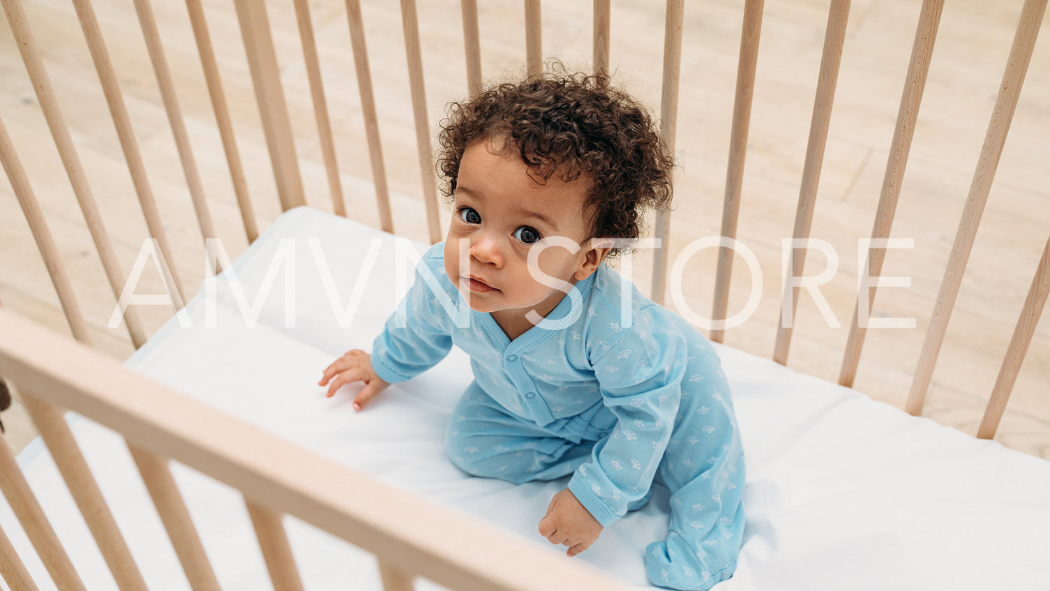 Portrait of cute baby boy sitting in crib at home	