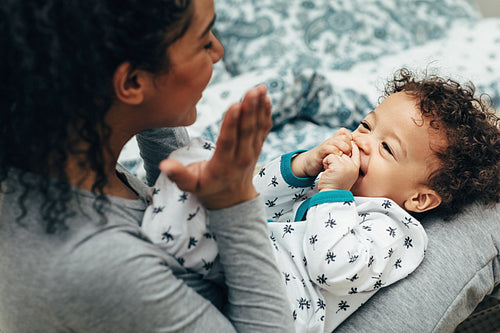 Mother holding baby on her lap and playing. Happy little boy looking at mother.