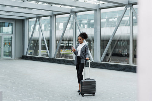 Young woman with luggage and cell phone preparing for business trip