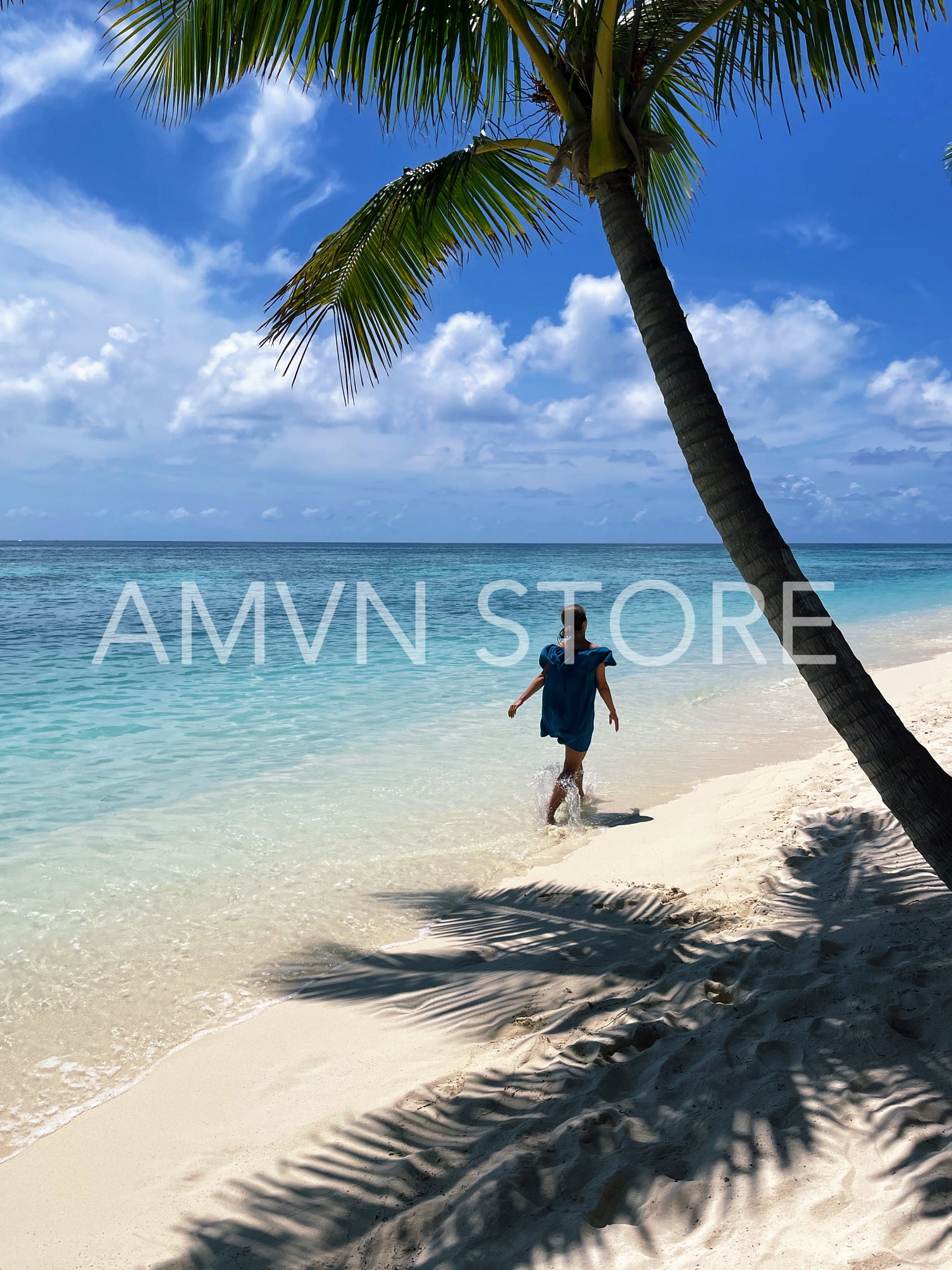 Back view of young woman walking on a tropical beach 