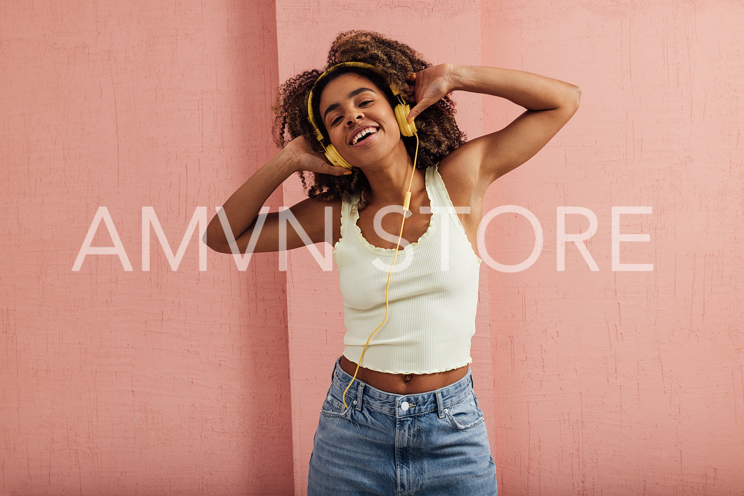 Happy woman enjoying music while standing against pink wall look