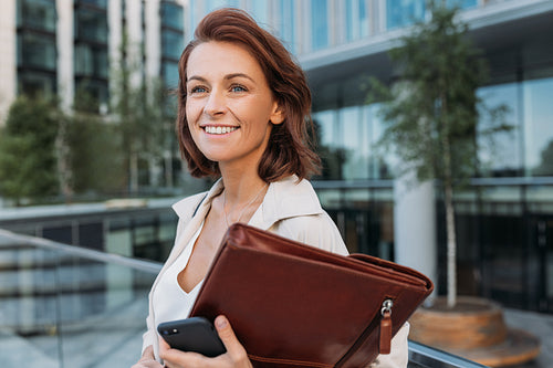 Portrait of a smiling businesswoman with ginger hair standing outdoors