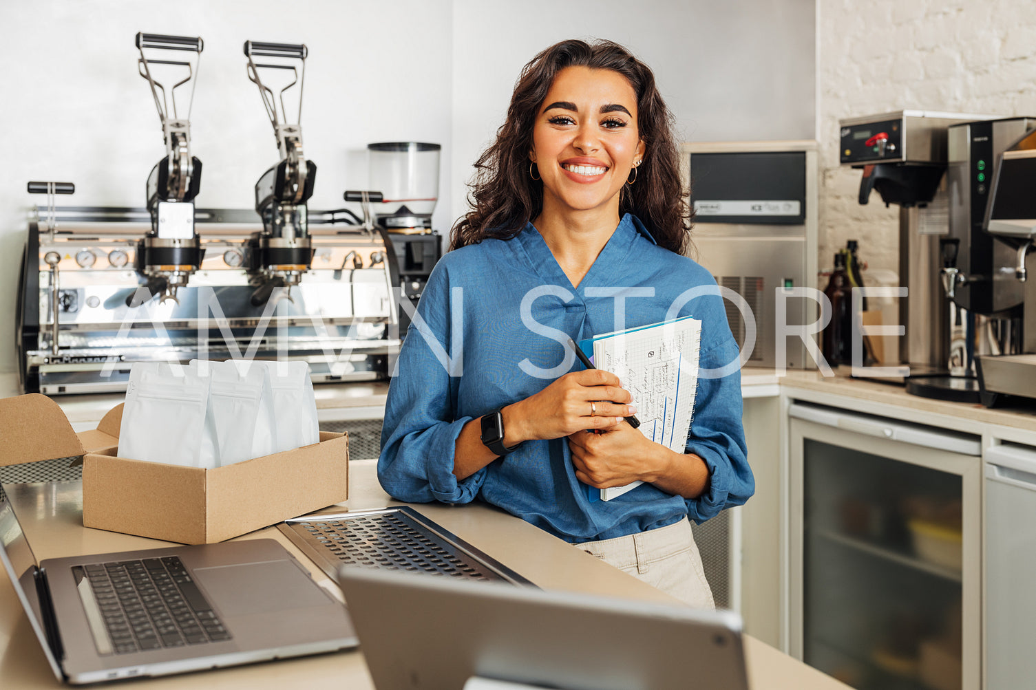 Portrait of a beautiful businesswoman standing in her coffee shop and holding a notebook. Small cafe owner looking at camera.