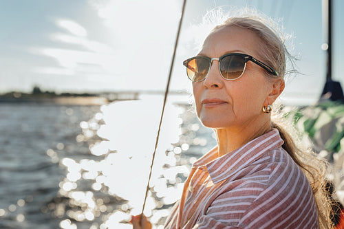 Portrait of a mature woman wearing sunglasses standing on a sailboat and looking into distance