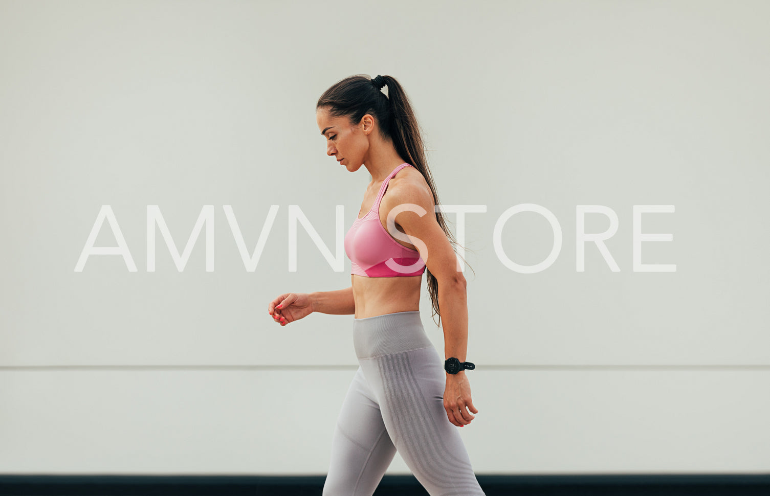 Side view of a slim female preparing to run outdoors. Young woman in fitness attire at a wall.