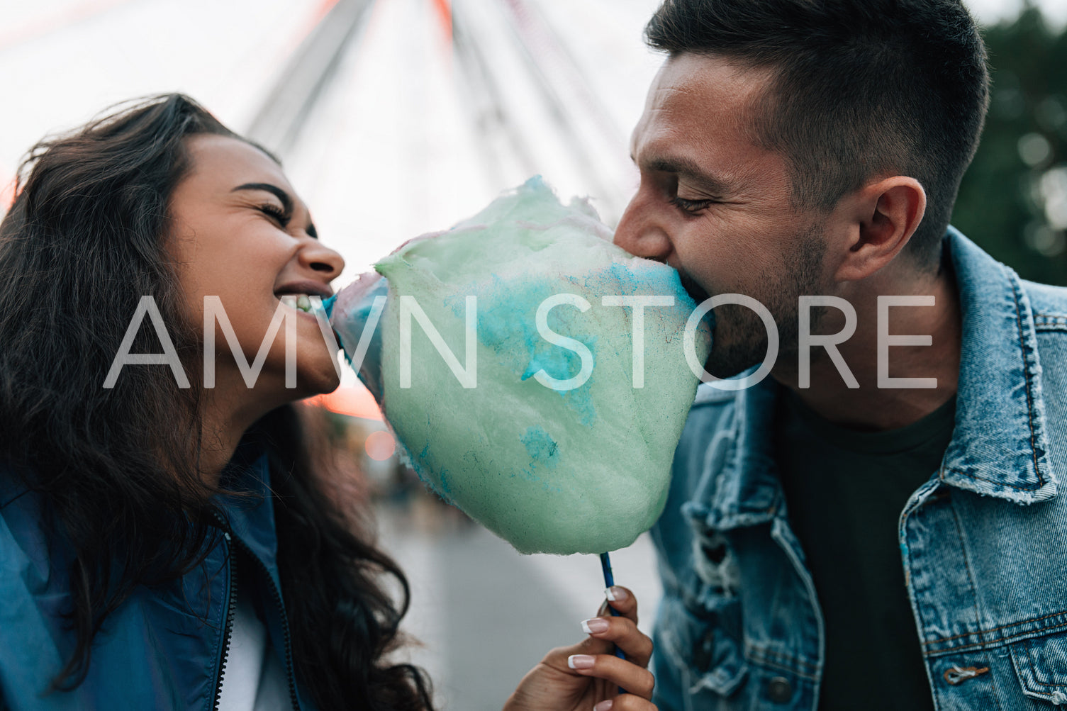 Man and woman biting cotton candy and having fun during festival