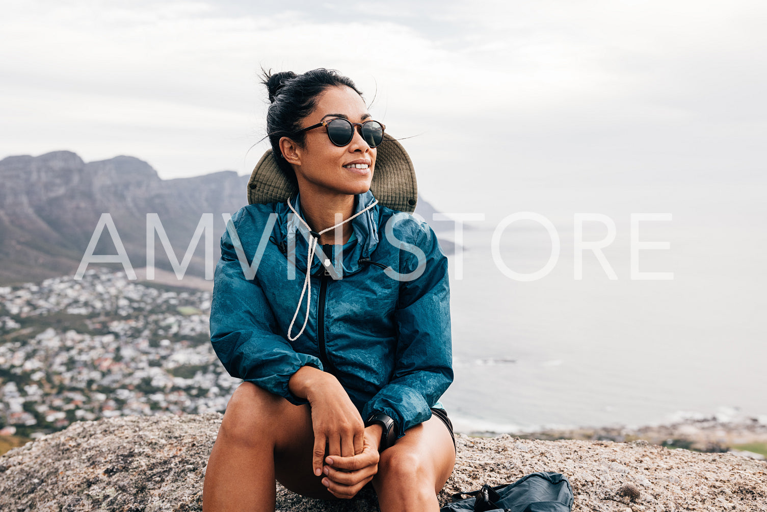 Young woman hiker enjoying the view while sitting on a mountain