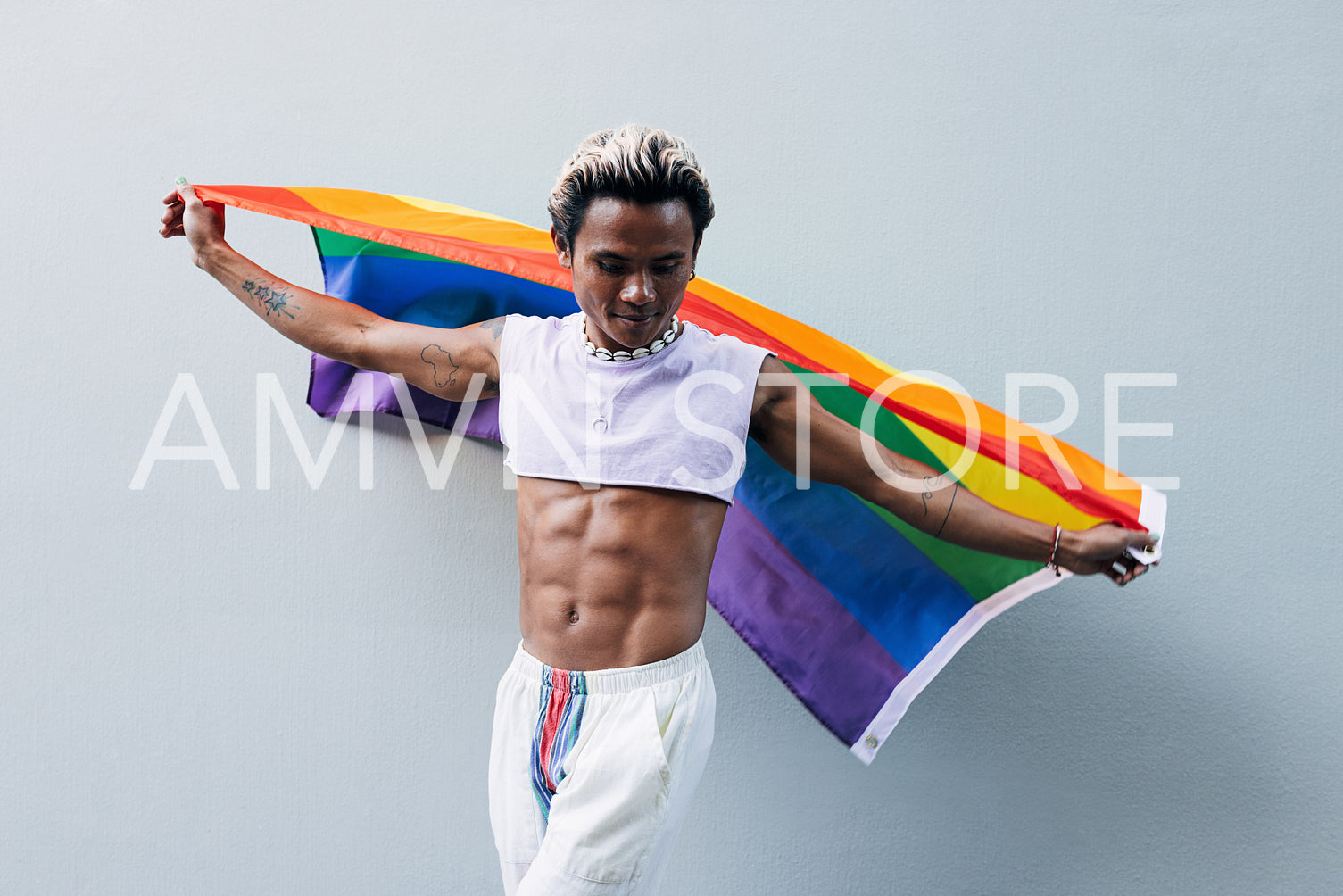 Stylish guy dancing with rainbow flag outdoors