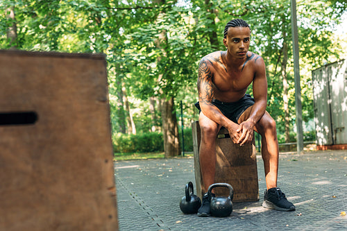 Young athlete resting during workout with kettlebells on the sports ground