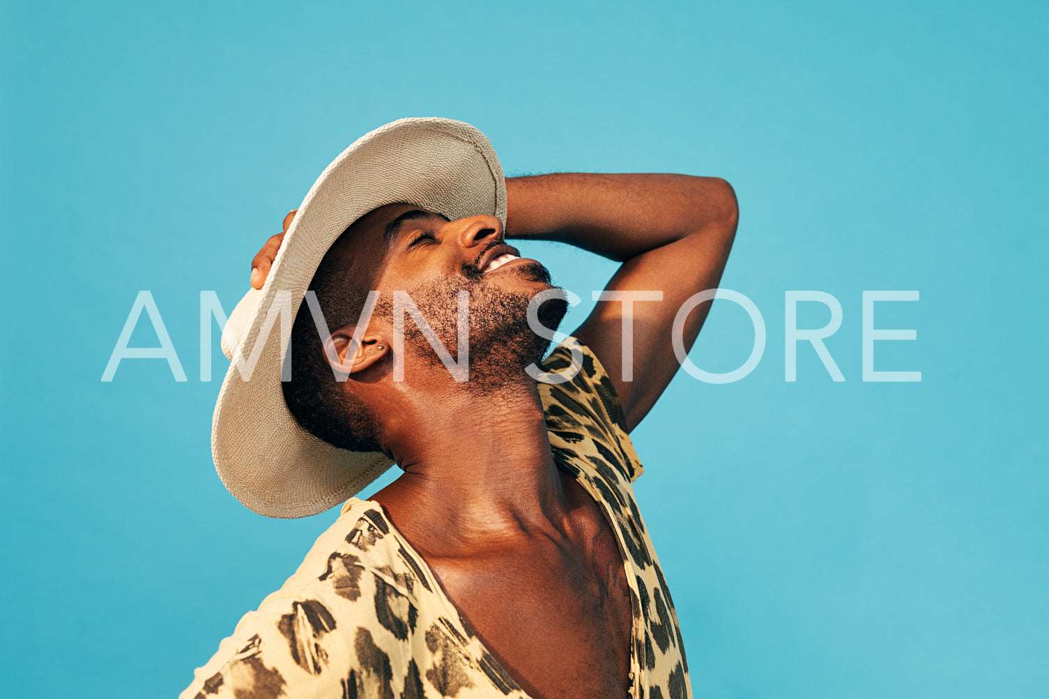 Cheerful man holds his straw hat standing with closed eyes