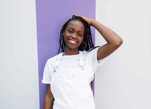 Happy woman with braids wearing white casual clothes and looking at camera outdoors