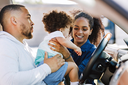 Smiling mother pulls son out of car. Family prepares for a trip.