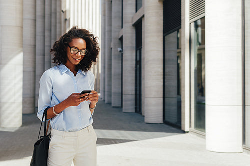 Woman texting from mobile phone near a office building