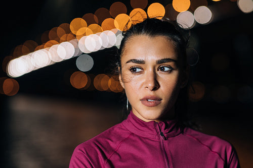 Portrait of a young sportswoman standing at night against city lights