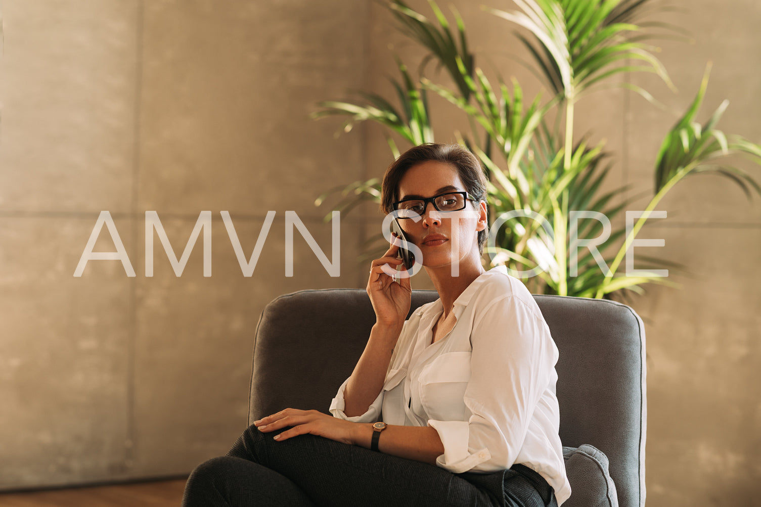 Portrait of a confident middle-aged businesswoman sitting on an armchair talking on a mobile phone