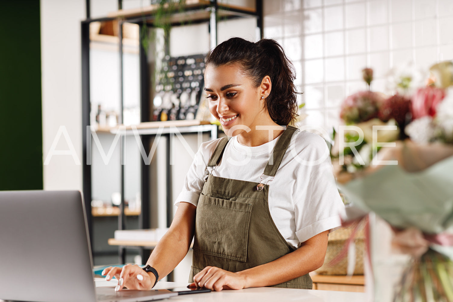 Young shop owner using a laptop. Florist woman standing at counter.	