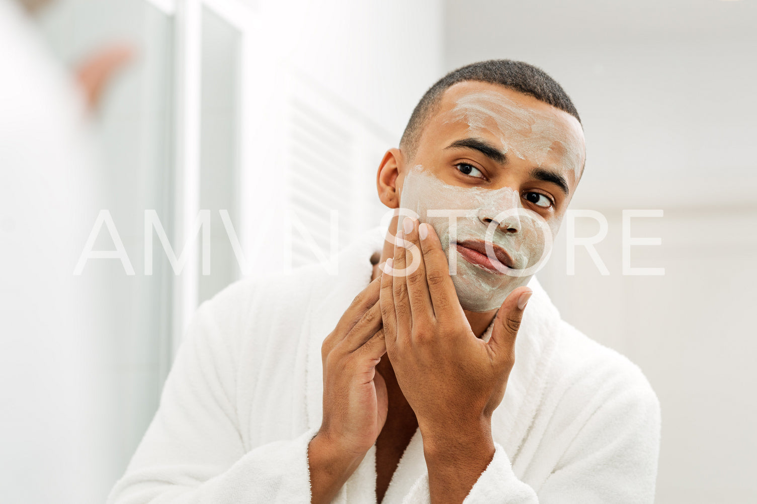 Man looking in the mirror with white clay mask on his face	