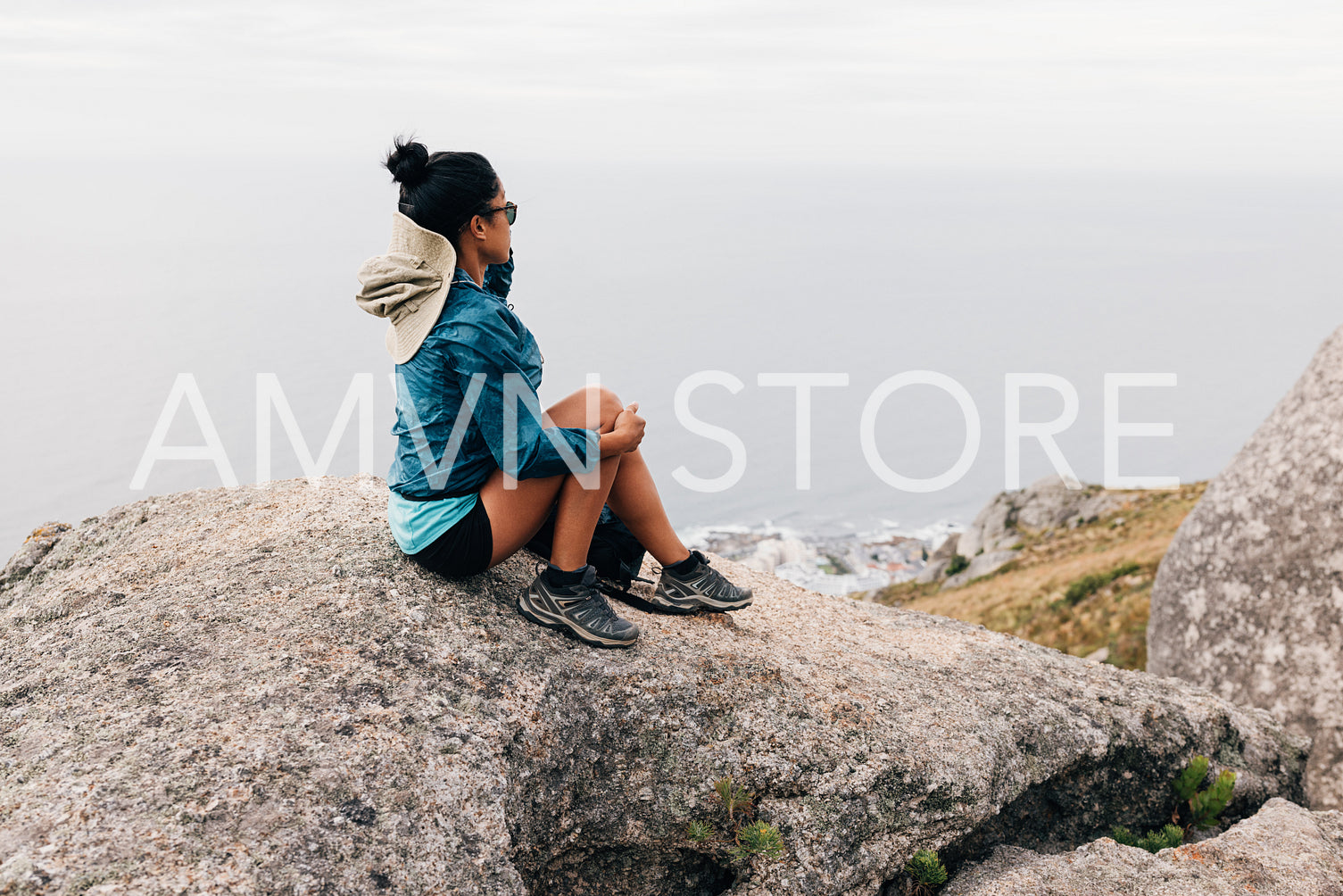 Rear view of woman sitting on the cliff looking at the view during hike