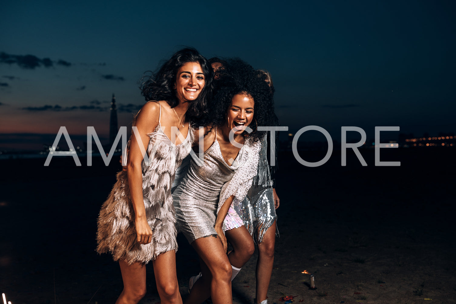 Laughing friends walking together at night outdoors looking at camera	