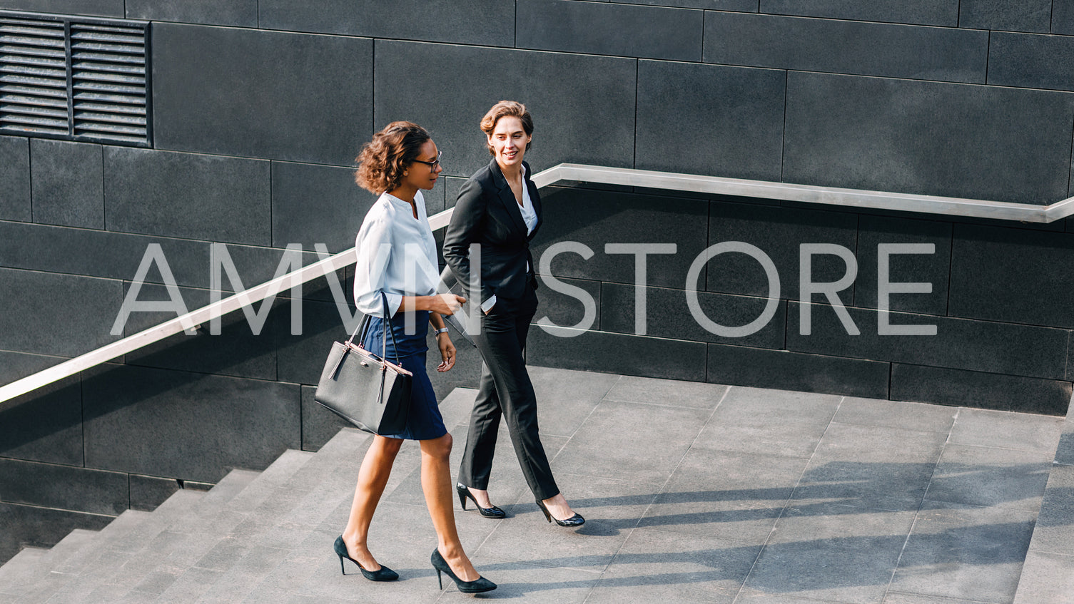 Two women in office wear walking outdoors and talking	