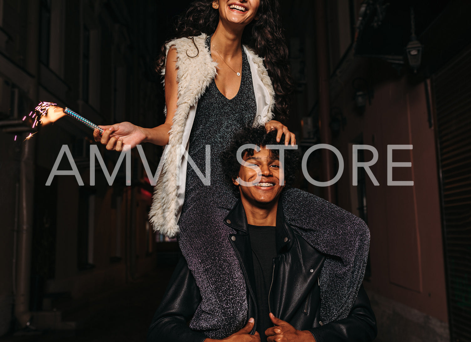 Smiling woman sitting on shoulders of her friend, holding a sparkler	