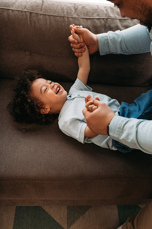 Happy little boy playing with his dad in living room