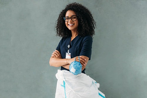 Smiling nurse wearing a medical uniform with badge holding a respirator looking at camera