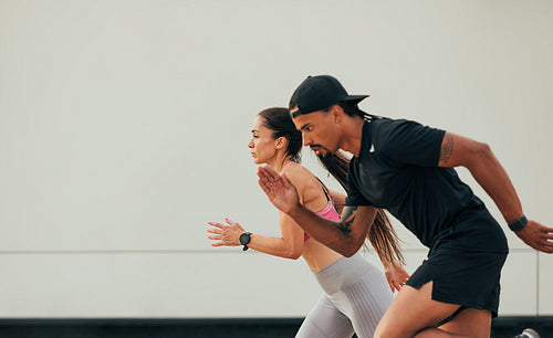 Side view of male and female runner exercising together at the wall