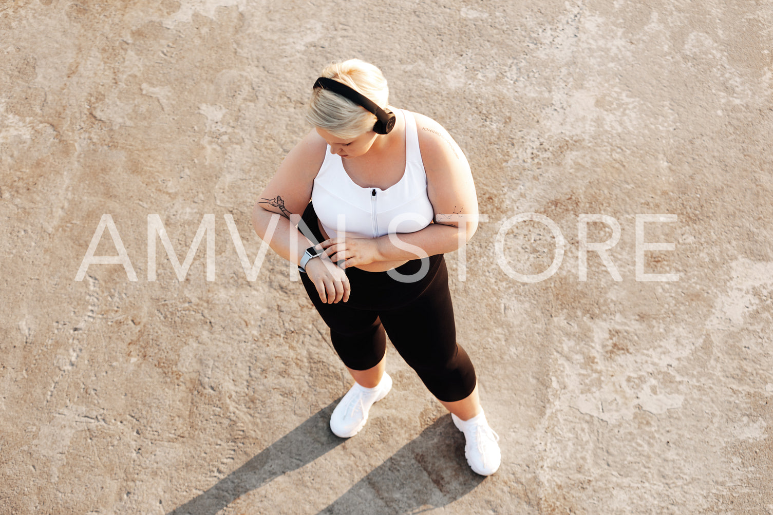 Shot from above of a young woman with plus size body checking activity tracker	