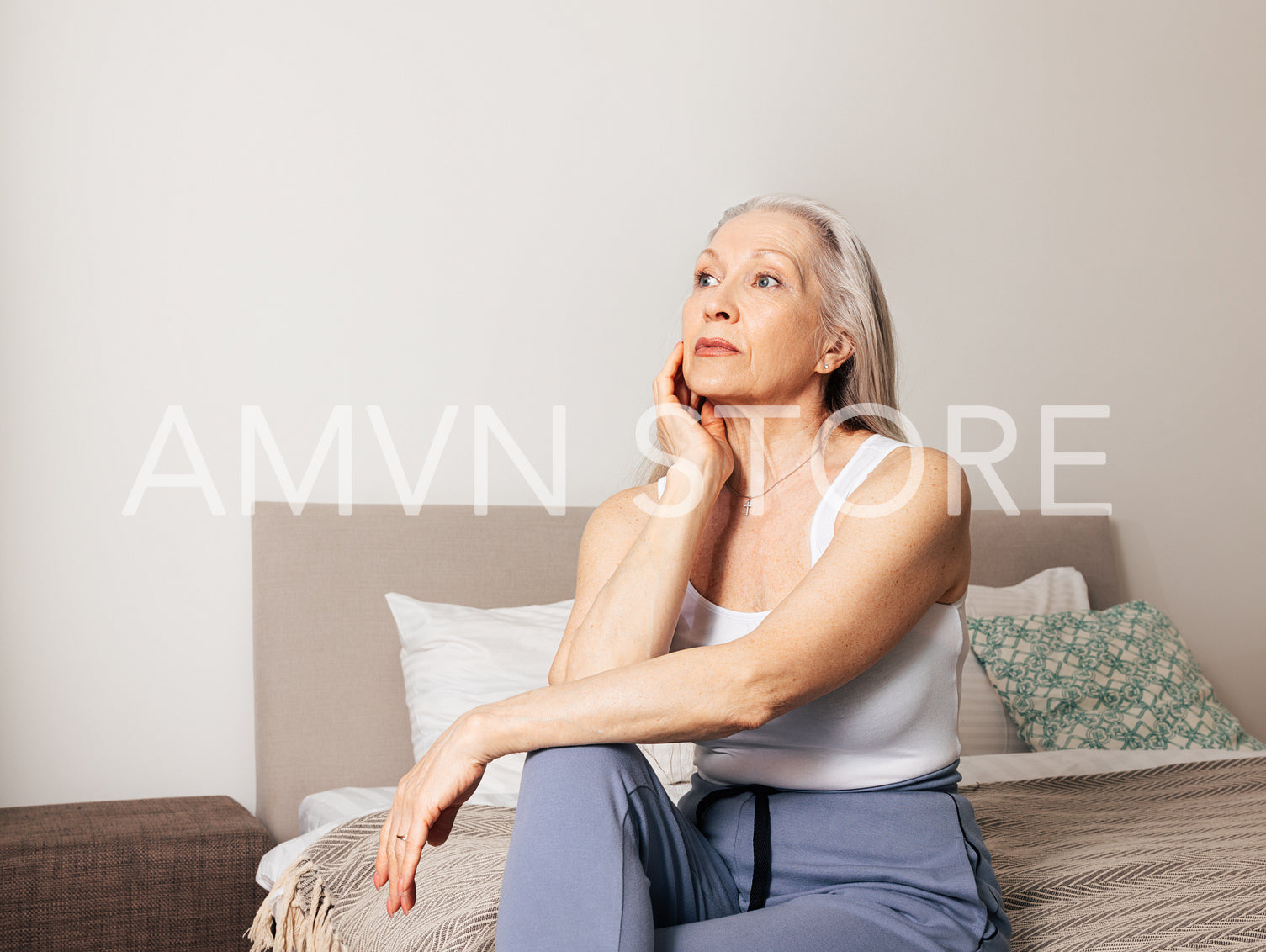 Frustrated senior female sitting on a bed in living room