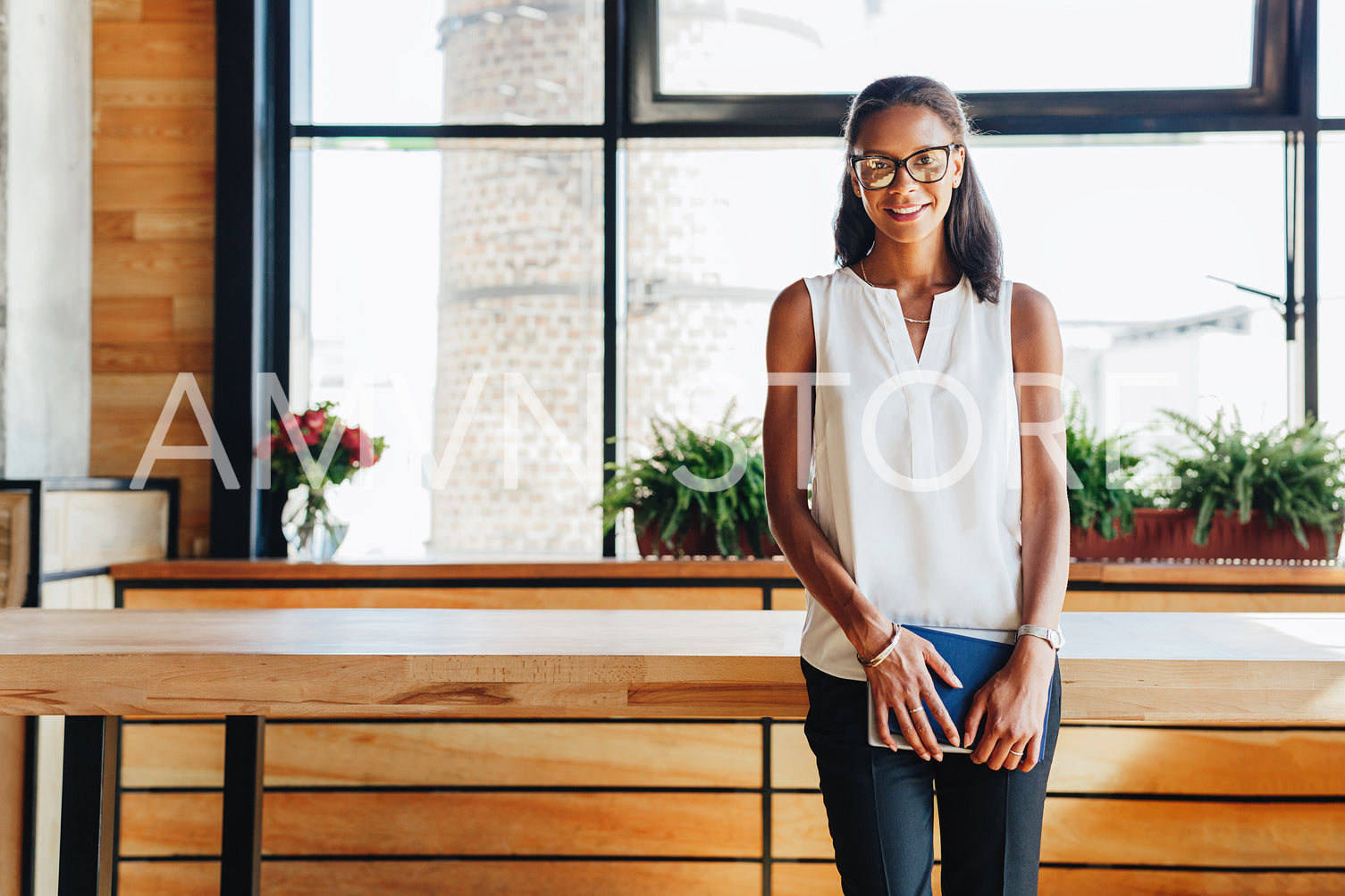 Portrait of successful young entrepreneur leaning to table in cafe	