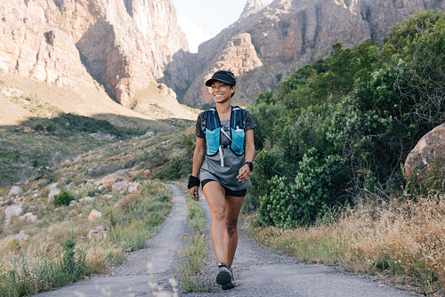 Woman walking on a country road. Young smiling female hiking in nature.