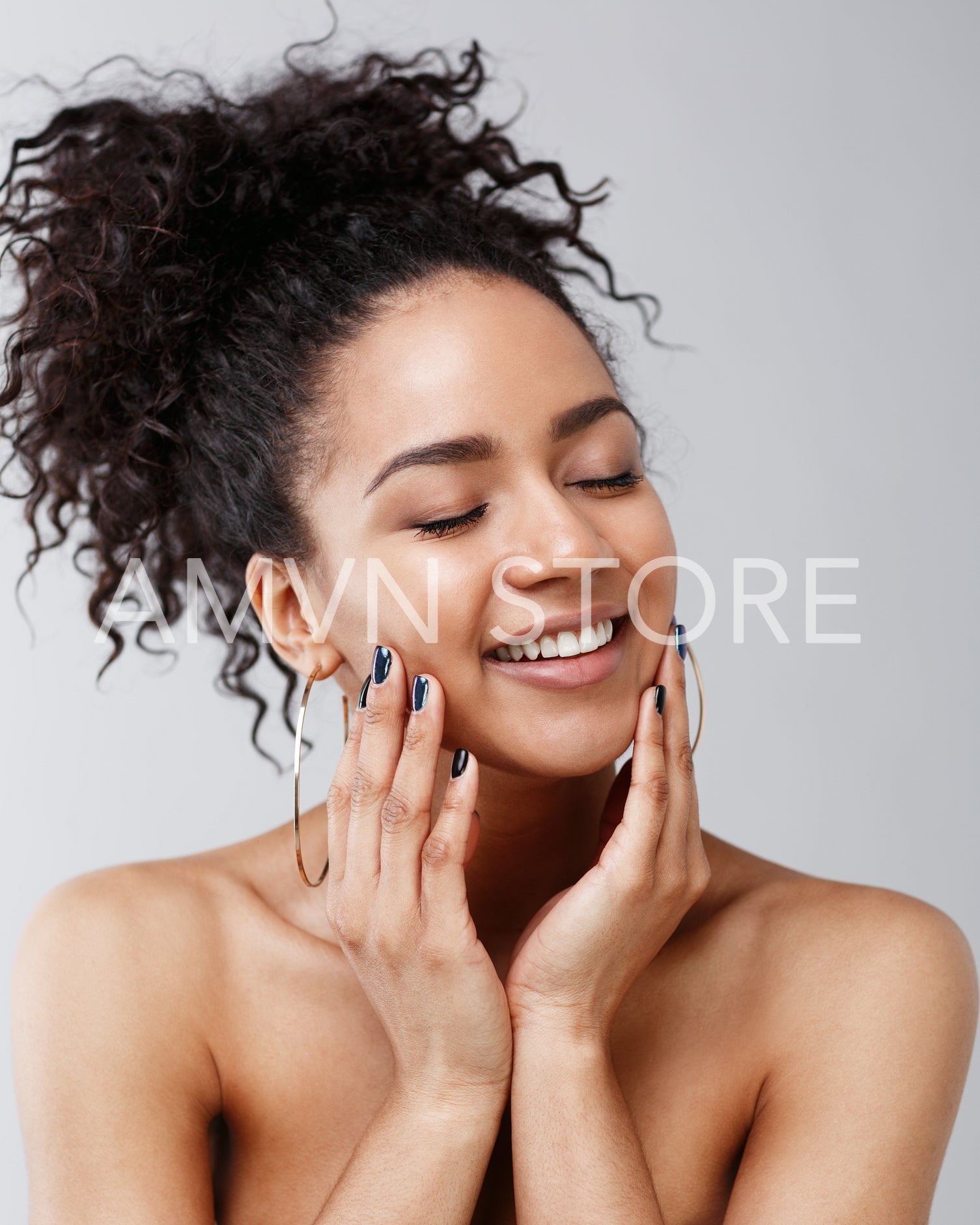 Portrait of beautiful young woman with hands on cheeks, studio shot	