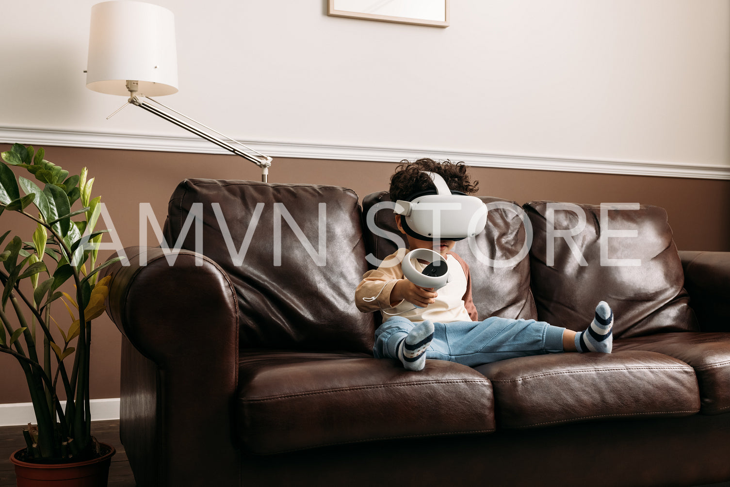 Little boy playing virtual reality game while sitting on sofa in