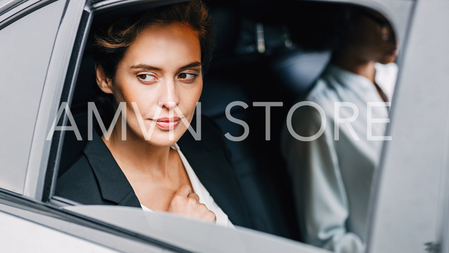 Pensive businesswoman sitting on back seat of a car and looking outside the window	