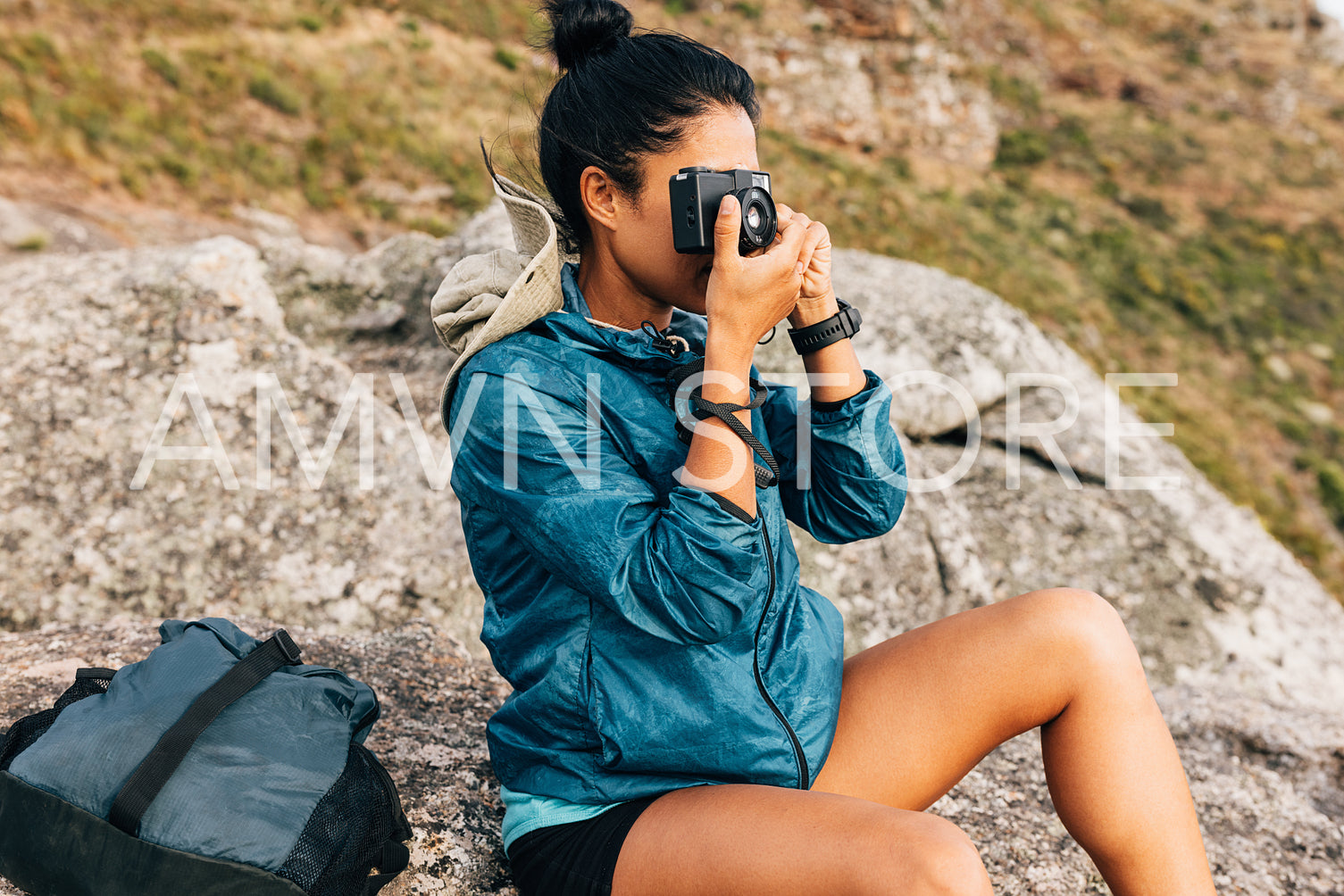 Woman tourist taking photographs on a film camera sitting on a rock