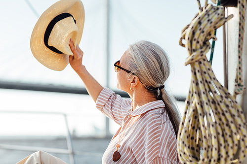 Woman on yacht uses a hat to hide her face from the sun