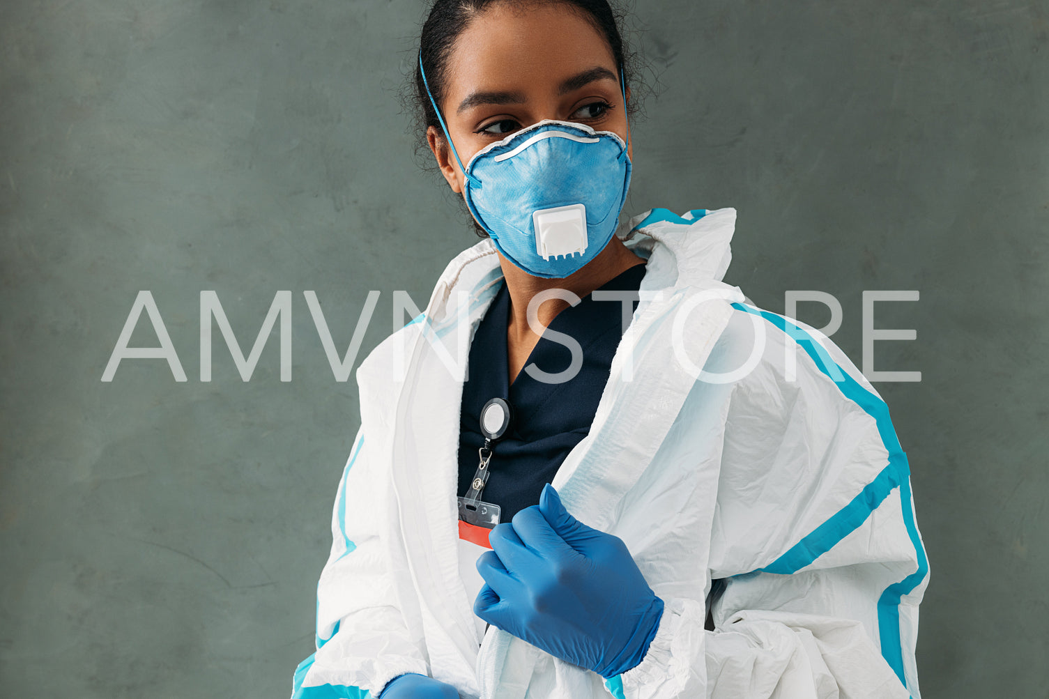 Female nurse zip up protective suit. Young doctor wearing FFP3 respirator and looking away.	