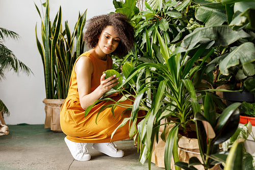 Young woman holding a book and observe a plant in workshop