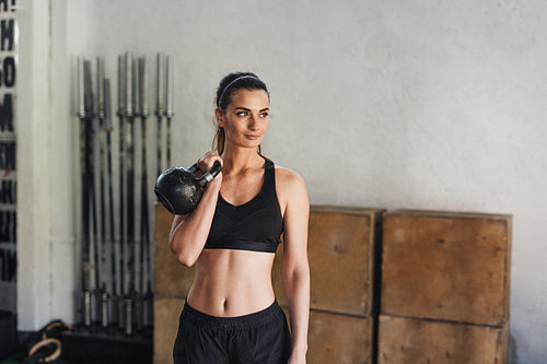 Young athlete in sportswear doing workout with kettlebell in sport club