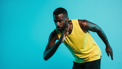 Portrait of a man on blue background in position to start a sprint