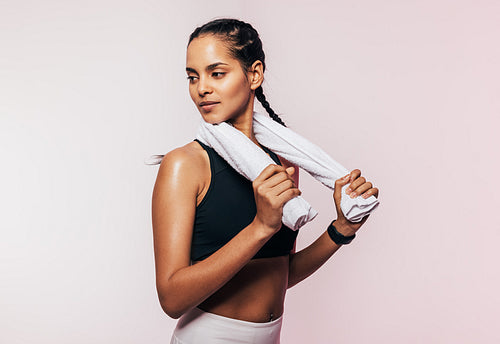 Portrait of a sportswoman with braids holding a white towel looking away