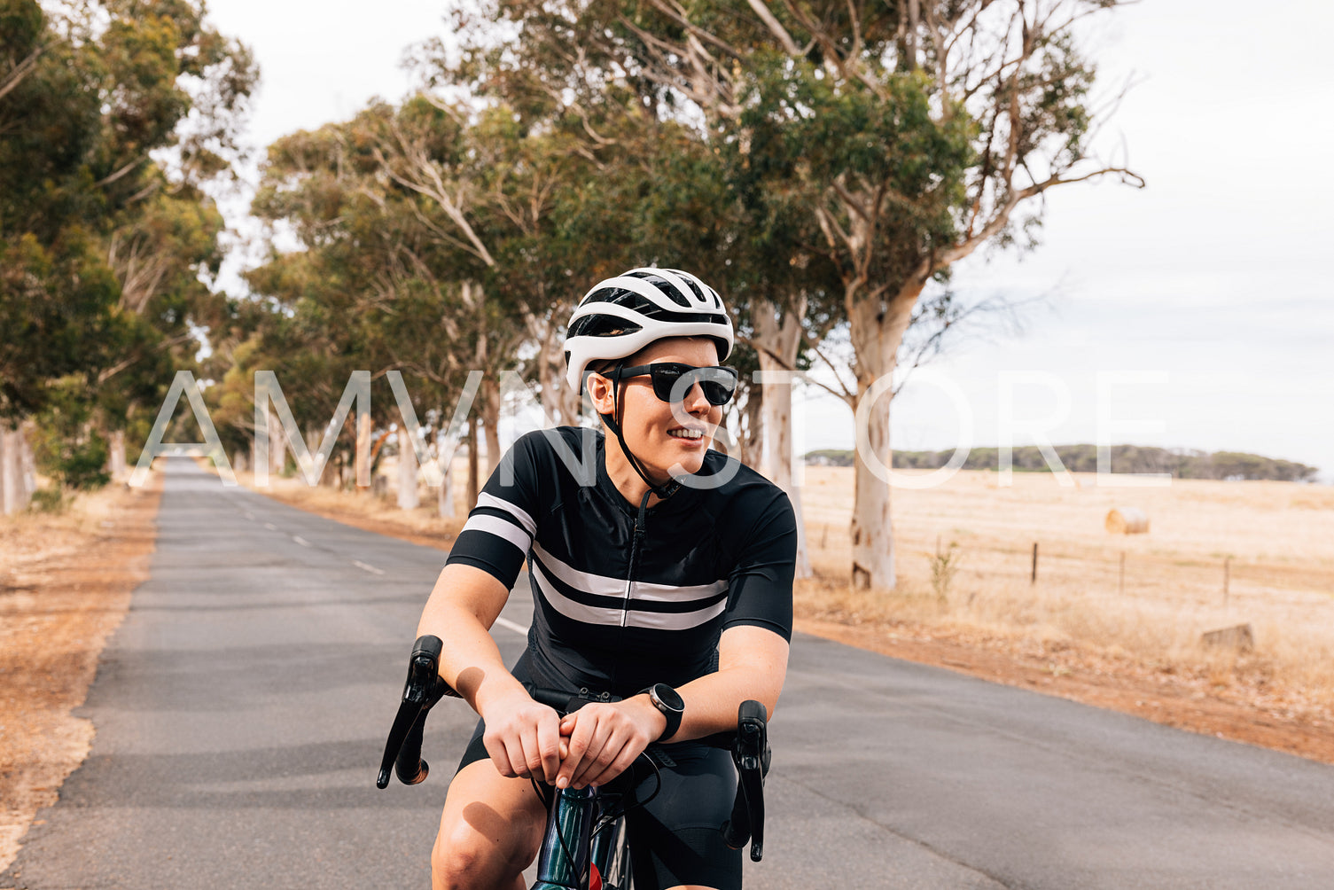 Smiling woman cyclist relaxing during ride on empty country road