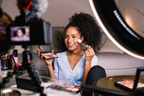 Beauty vlogger making a video tutorial on makeup in living room